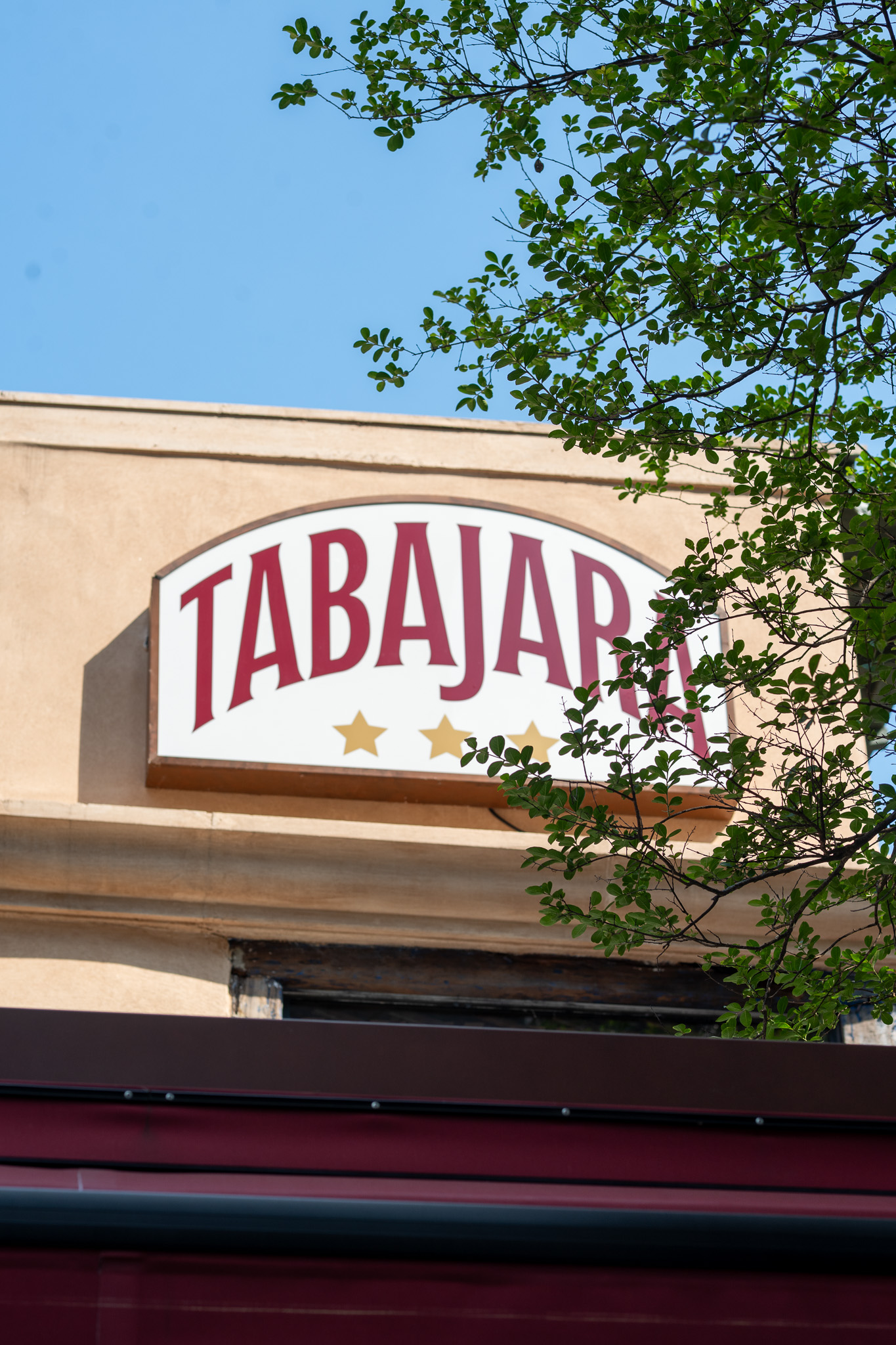 Placa do Tabajara na fachada, entre as árvores