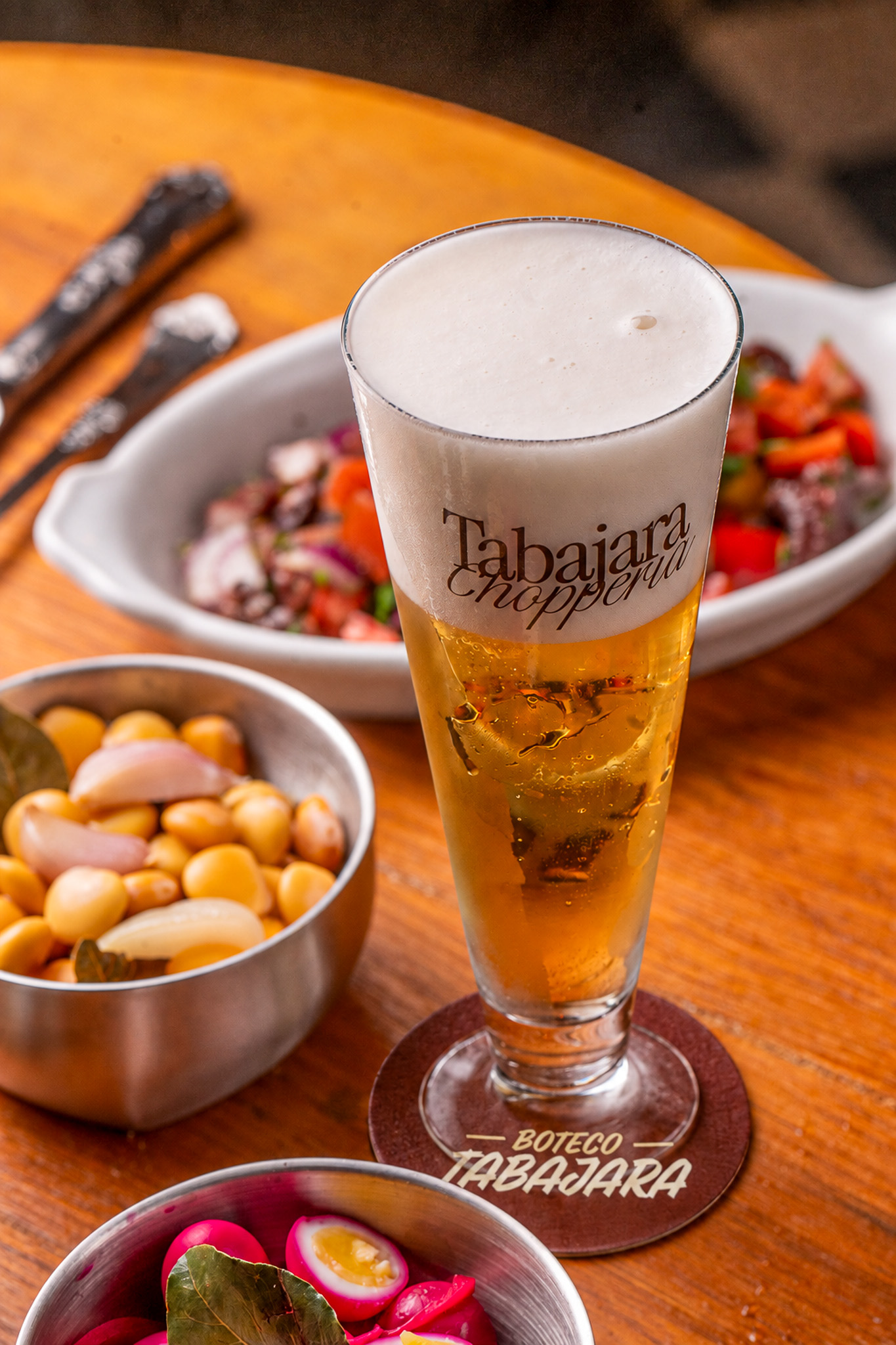Tulipa de chopp Tabajara na mesa, com petiscos